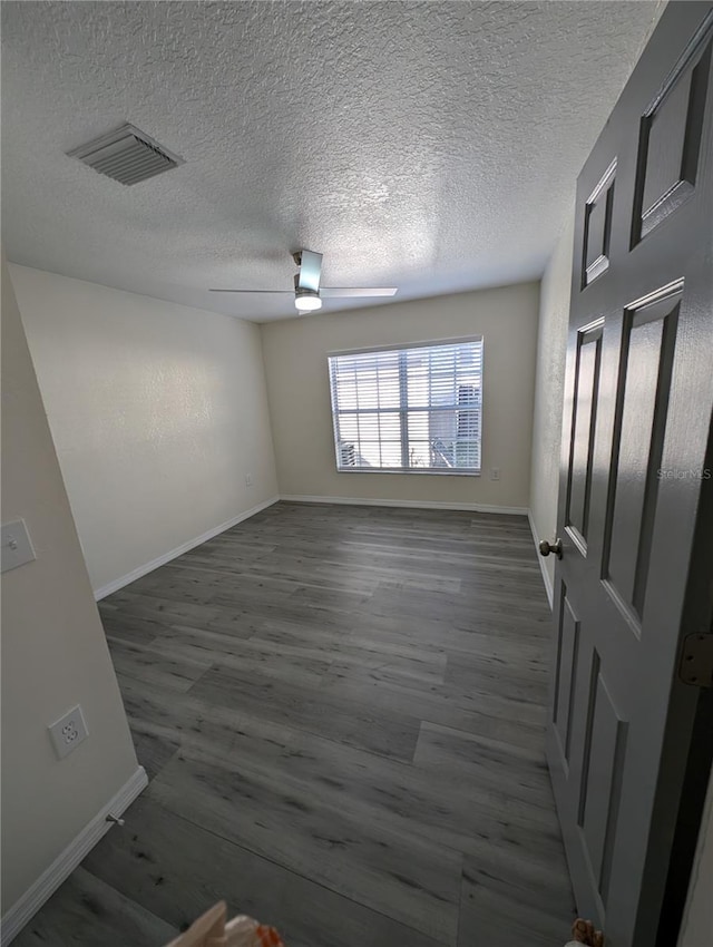 unfurnished room with a textured ceiling, ceiling fan, and dark wood-type flooring