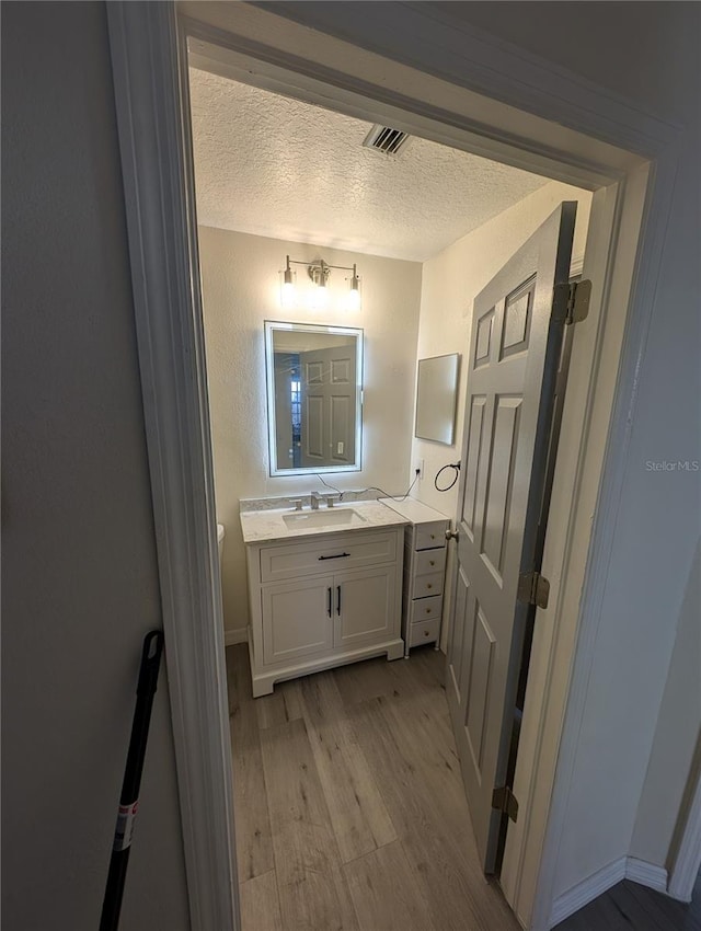 bathroom featuring hardwood / wood-style floors, vanity, and a textured ceiling