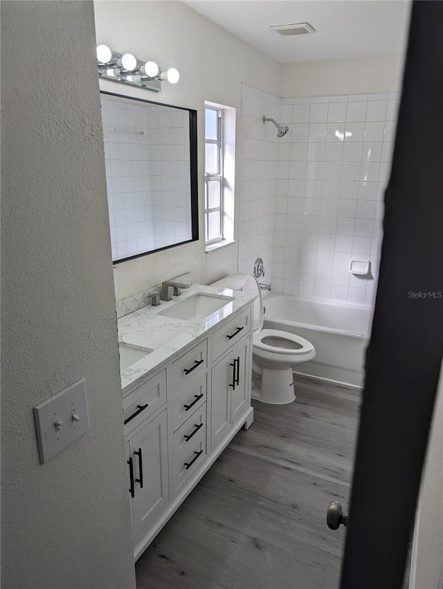 full bathroom with vanity, toilet, wood-type flooring, and tiled shower / bath combo