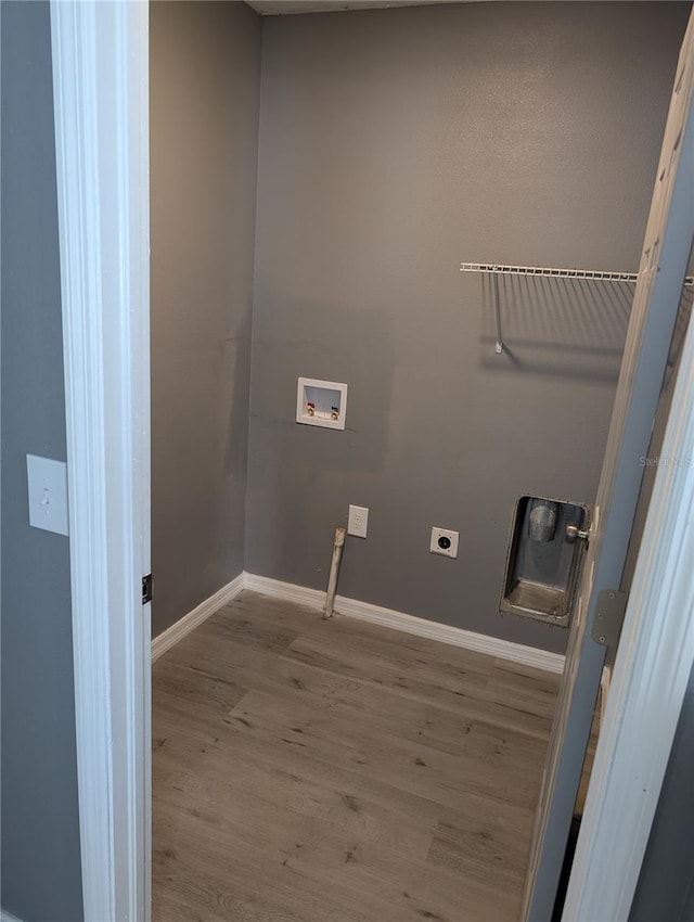 clothes washing area featuring electric dryer hookup, light hardwood / wood-style floors, and hookup for a washing machine