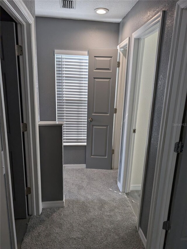 hallway with carpet and a textured ceiling