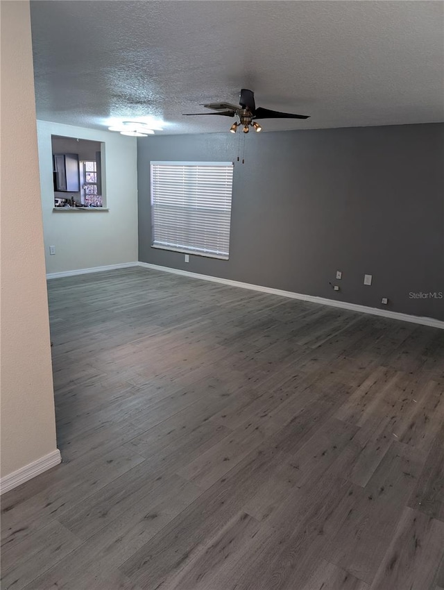 empty room with ceiling fan, wood-type flooring, and a textured ceiling