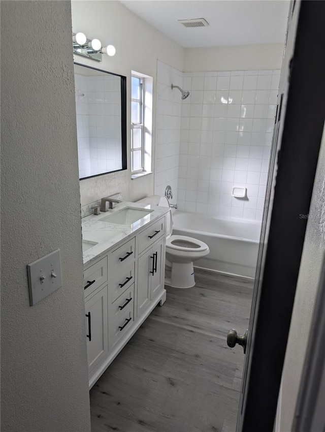 full bathroom with vanity, toilet, wood-type flooring, and tiled shower / bath