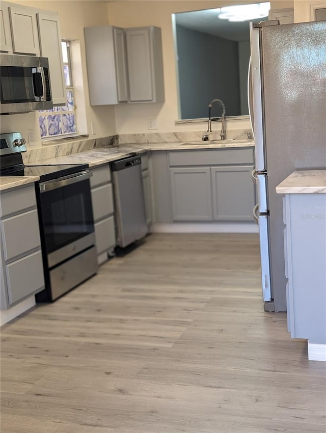 kitchen with sink, stainless steel appliances, and light hardwood / wood-style flooring