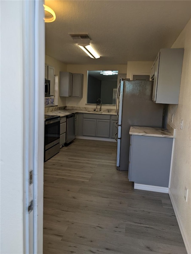 kitchen with dark hardwood / wood-style floors, gray cabinets, sink, and stainless steel appliances