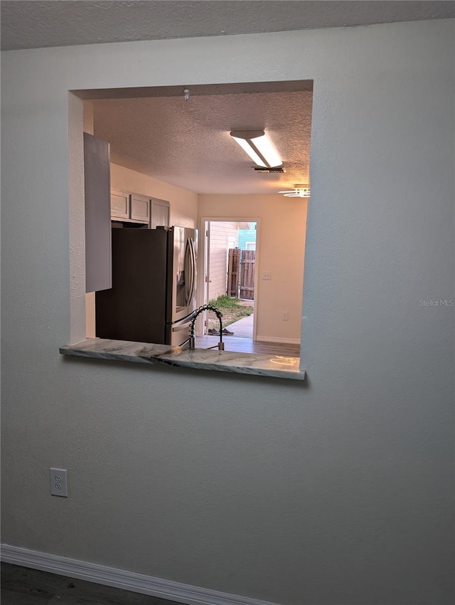 kitchen featuring white cabinets, stainless steel fridge with ice dispenser, sink, and a textured ceiling