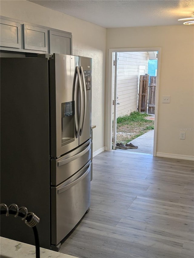 kitchen featuring stainless steel fridge with ice dispenser and light hardwood / wood-style flooring