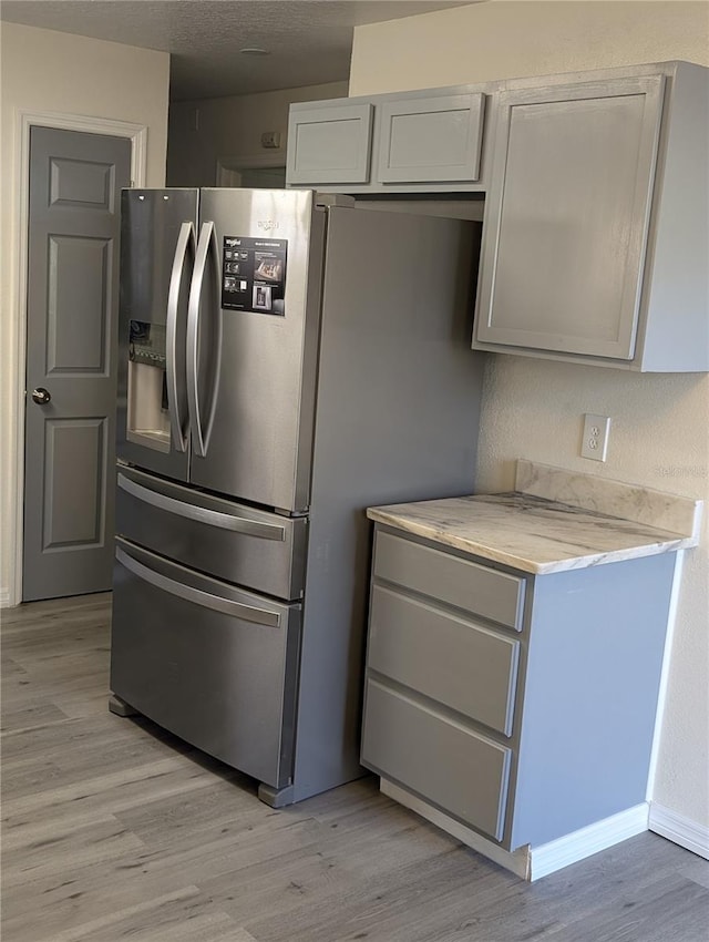 kitchen with stainless steel fridge, light wood-type flooring, and gray cabinetry