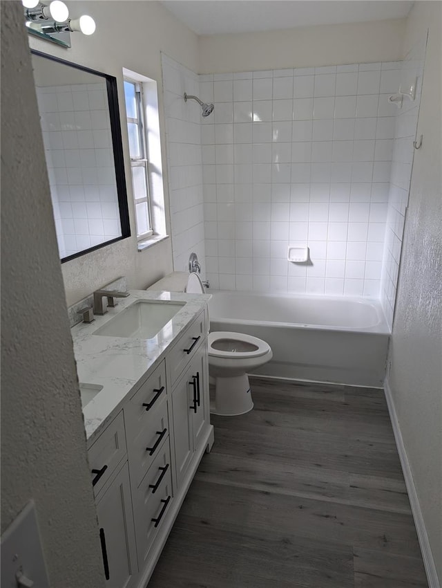 full bathroom featuring tiled shower / bath, vanity, wood-type flooring, and toilet