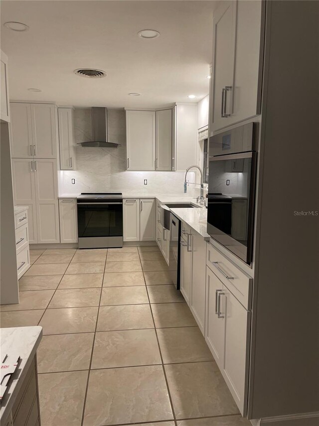 kitchen featuring wall chimney range hood, white cabinetry, sink, and appliances with stainless steel finishes