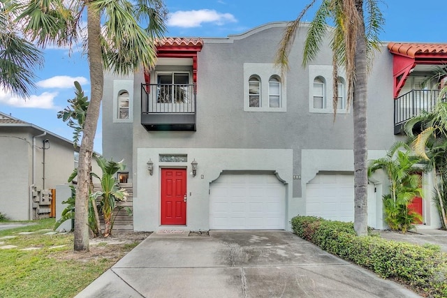 view of front of home with concrete driveway, a balcony, a garage, and stucco siding