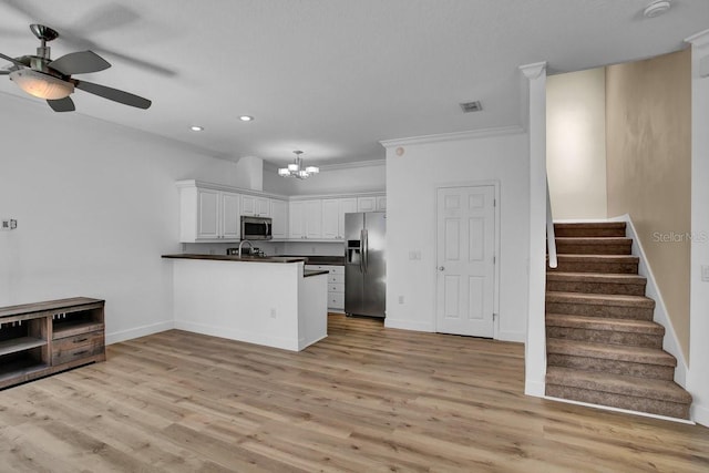 kitchen featuring visible vents, ceiling fan with notable chandelier, dark countertops, stainless steel appliances, and a peninsula