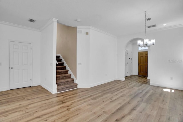 interior space featuring crown molding, arched walkways, visible vents, and light wood-type flooring