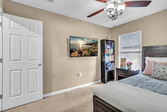 bedroom with ceiling fan, a textured ceiling, baseboards, and light carpet
