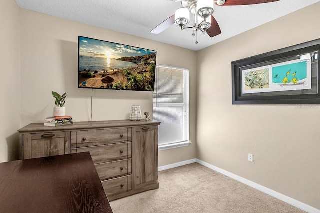 home office with light colored carpet, a textured ceiling, baseboards, and a ceiling fan