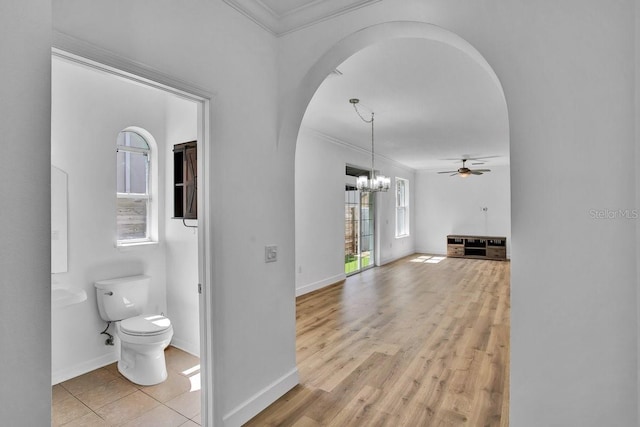 bathroom featuring baseboards, toilet, ornamental molding, ceiling fan with notable chandelier, and wood finished floors