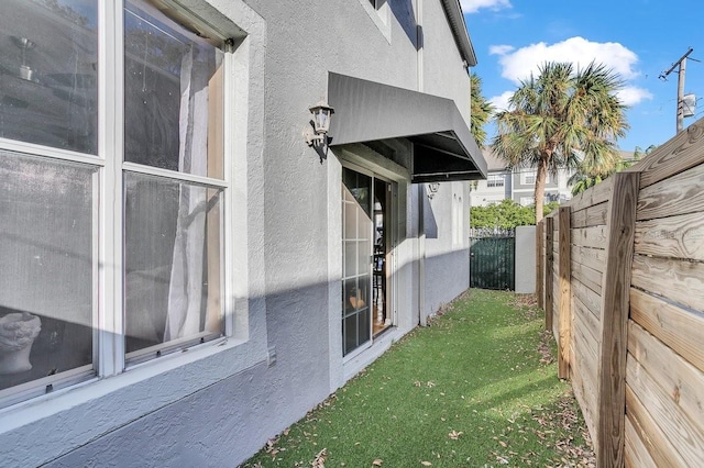 view of side of property with stucco siding and fence