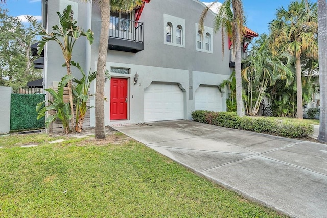 view of front facade with a balcony, driveway, an attached garage, stucco siding, and a front lawn