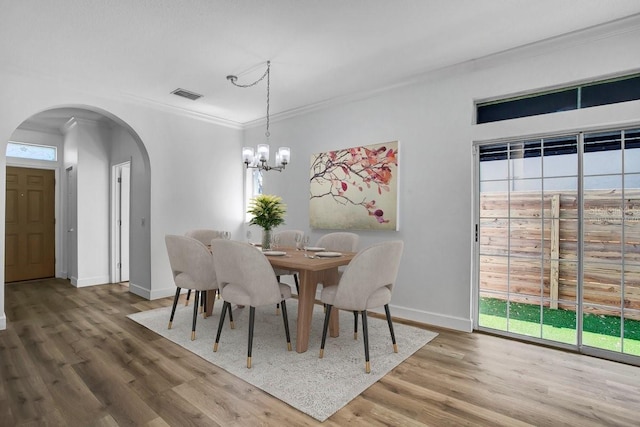 411 S Fremont Ave Unit B, Tampa, FL 33606 - dining area featuring arched walkways, wood finished floors, a chandelier, crown molding, and baseboards