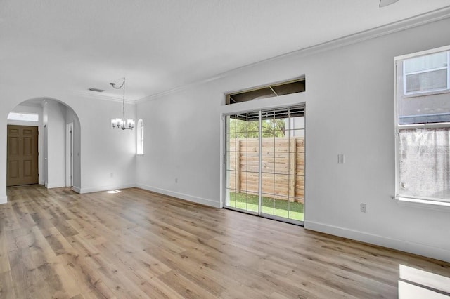 411 S Fremont Ave Unit B, Tampa, FL 33606 - empty room featuring arched walkways, ornamental molding, a chandelier, light wood-type flooring, and baseboards