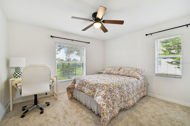 bedroom featuring light carpet, multiple windows, and ceiling fan