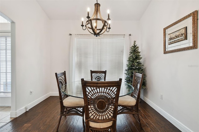 dining space with dark wood-type flooring and a notable chandelier