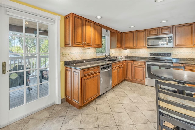 kitchen with sink, light tile patterned floors, a healthy amount of sunlight, and appliances with stainless steel finishes