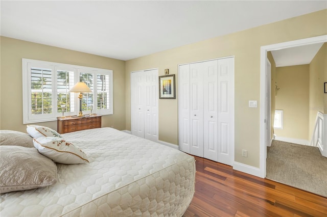 bedroom featuring dark hardwood / wood-style floors and two closets