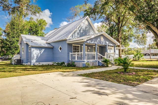 view of front of home with central AC unit, a porch, and a front lawn