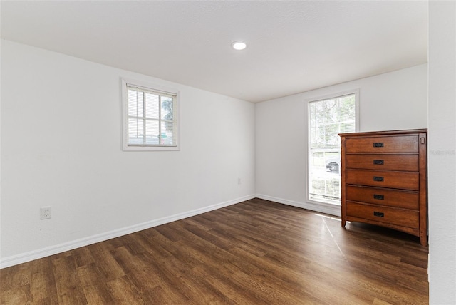 empty room featuring plenty of natural light and dark hardwood / wood-style flooring