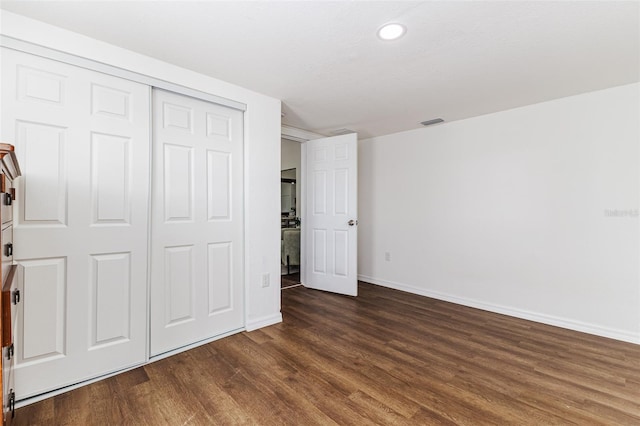 unfurnished bedroom with dark hardwood / wood-style flooring and a closet