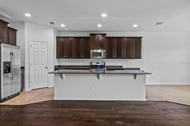 kitchen with an island with sink, a kitchen breakfast bar, and stainless steel appliances