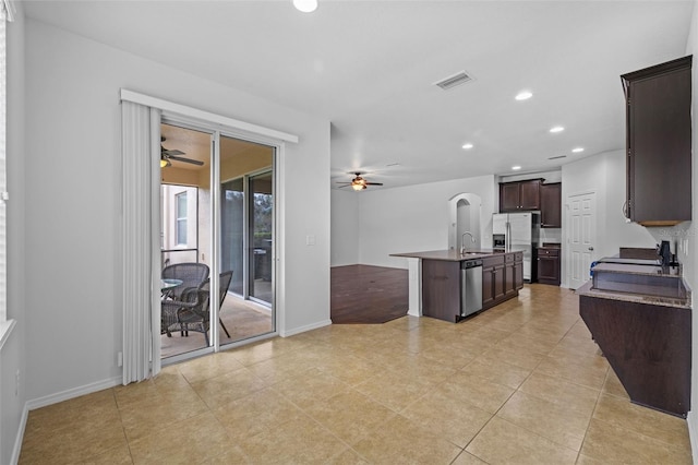 kitchen featuring appliances with stainless steel finishes, dark brown cabinets, sink, ceiling fan, and a kitchen island with sink