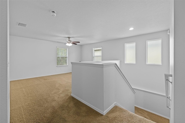 hall featuring a textured ceiling and light carpet