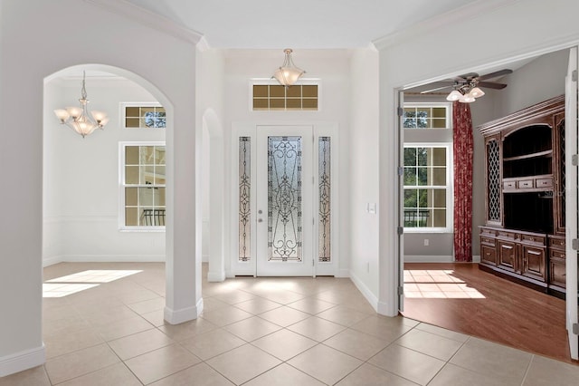 foyer with crown molding, light tile patterned floors, and ceiling fan with notable chandelier