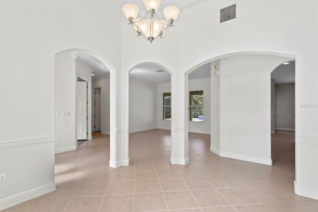 tiled empty room featuring a chandelier and ornamental molding