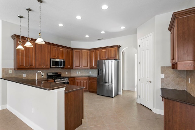 kitchen with kitchen peninsula, pendant lighting, stainless steel appliances, and tasteful backsplash