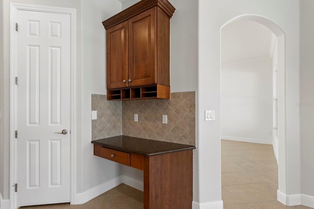 kitchen with decorative backsplash, light tile patterned flooring, and dark stone countertops