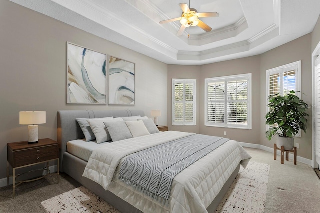 bedroom featuring ceiling fan, crown molding, light carpet, and a tray ceiling