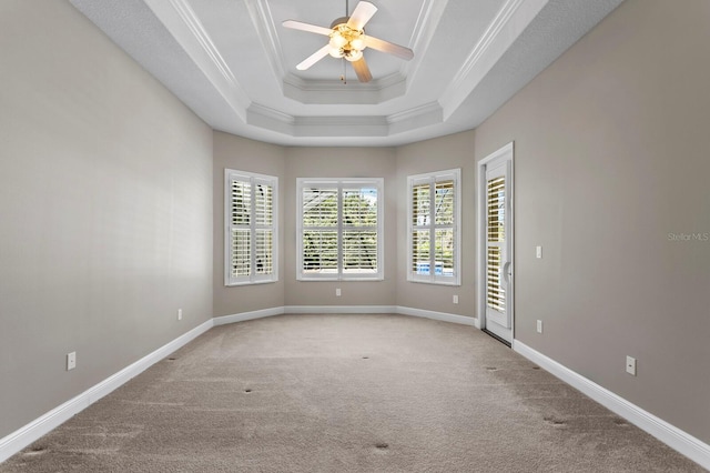 unfurnished room featuring a tray ceiling, ceiling fan, crown molding, and light colored carpet