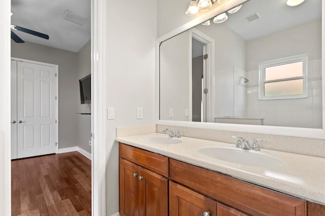 bathroom with tiled shower, vanity, hardwood / wood-style flooring, and ceiling fan