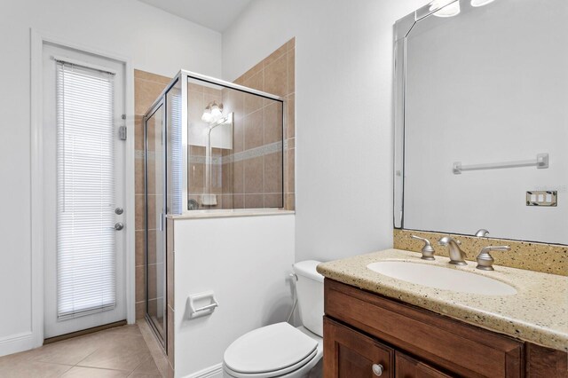 bathroom with tile patterned floors, a shower with door, vanity, and toilet