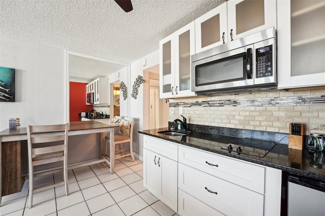 kitchen featuring dark stone countertops, white cabinets, and sink