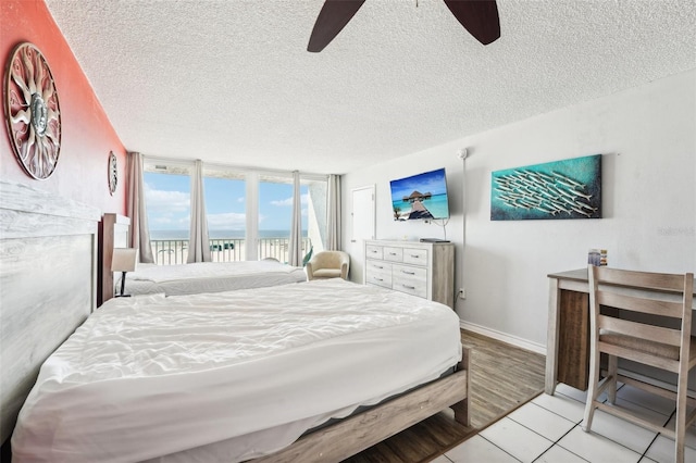 bedroom featuring access to exterior, floor to ceiling windows, a textured ceiling, ceiling fan, and light wood-type flooring