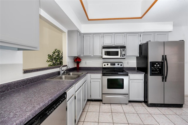 kitchen with dark countertops, light tile patterned floors, stainless steel appliances, and a sink