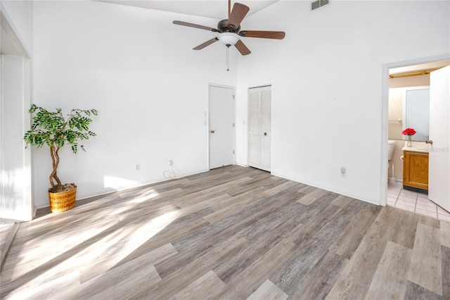 unfurnished bedroom with ceiling fan, light wood finished floors, connected bathroom, and visible vents