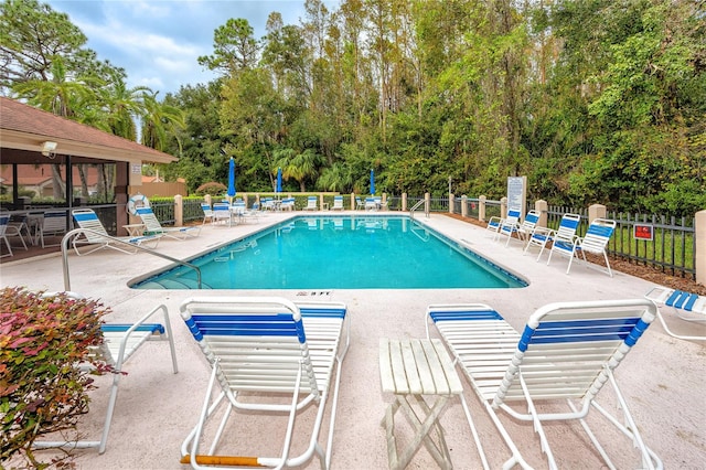 community pool with a patio and fence