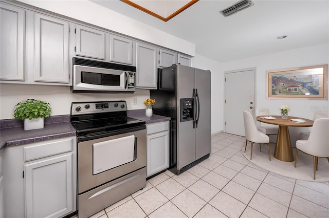 kitchen featuring dark countertops, light tile patterned floors, visible vents, and stainless steel appliances