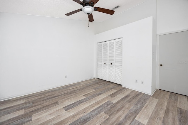 unfurnished bedroom featuring a closet, visible vents, ceiling fan, and wood finished floors