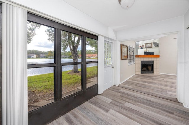 entryway featuring wood finished floors, a water view, a fireplace, and baseboards